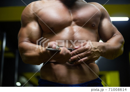 Close up of a man's toned naked body putting on a weightlifting belt before training in the gym Close up of a man's toned naked body putting on a weightlifting belt before training in the gym 71008614