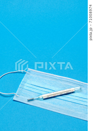 Protective medical face mask and Thermometer on a blue background - Top view with copy space Protective medical face mask and Thermometer on a blue background - Top view with copy space 71008974