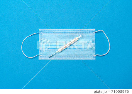 Protective medical face mask and Thermometer on a blue background - Top view with copy space 71008976