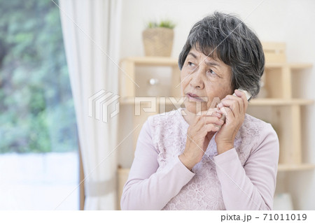 不審な電話に出るシニア女性 71011019