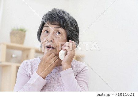 不審な電話に出るシニア女性 71011021