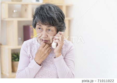 不審な電話に出るシニア女性 71011022