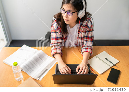 Young Asian female student working and studying from home during the city lockdown due to the spreading of corona virus Young Asian female student working and studying from home during the city lockdown due to the spreading of corona virus 71011430