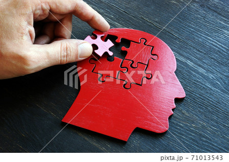 Treating mental illness and memory problems. The hand puts a piece of the puzzle on the shape of the head. Treating mental illness and memory problems. The hand puts a piece of the puzzle on the shape of the head. 71013543