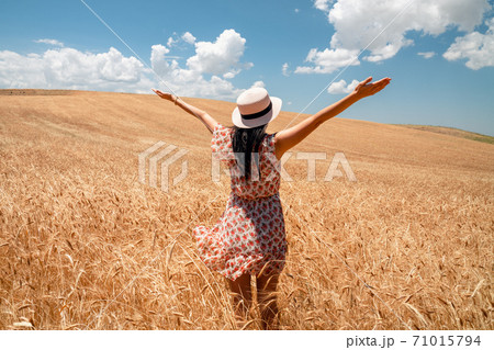 Beautiful woman is looking to the weath field with blue sky and clouds background. Farming and rural concept. Beautiful woman is looking to the weath field with blue sky and clouds background. Farming and rural concept. 71015794