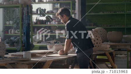 Male ceramist kneading clay in spacious studio Male ceramist kneading clay in spacious studio 71015963