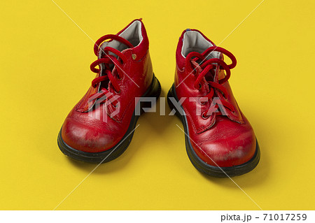 Children's leather shoes in red on a yellow background. Care for health. 71017259
