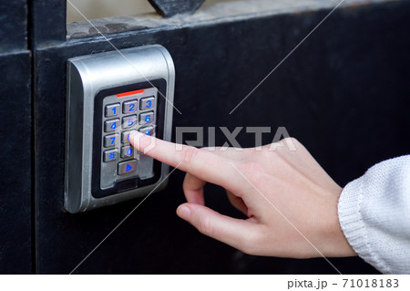 female hand dials the access code on the electronic lock by pressing a finger with a blue backlight, close-up of the security lock with the hand. female hand dials the access code on the electronic lock by pressing a finger with a blue backlight, close-up of the security lock with the hand. 71018183