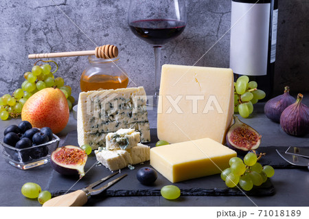 Blue cheese and parmesan on a black board, fruit, wine and honey. Close-up. Blue cheese and parmesan on a black board, fruit, wine and honey. Close-up. 71018189