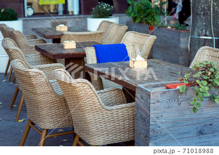 wooden tables and wicker chairs fenced with large flowerpots with flowers, nobody. wooden tables and wicker chairs fenced with large flowerpots with flowers, nobody. 71018988