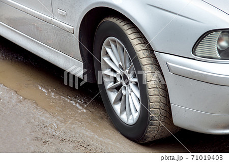 Wheel of a dirty car standing in a swamp, closeup of the wheel and front fender. Wheel of a dirty car standing in a swamp, closeup of the wheel and front fender. 71019403