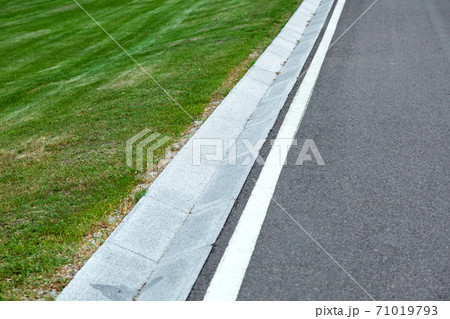 Street gutter of a stormwater drainage system on the side of an road with markings and grass. Street gutter of a stormwater drainage system on the side of an road with markings and grass. 71019793