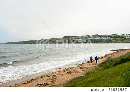 スコットランド郊外のセントアンドリュースの海岸 散歩する人々と遠くに見える家並み スコットランド郊外のセントアンドリュースの海岸 散歩する人々と遠くに見える家並み 71021987