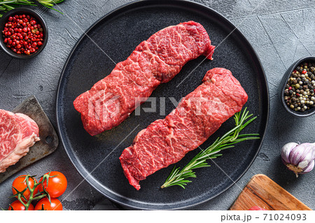 Raw set of denver steaks ob black plate raw organic food , marbled beef with herbs tomatoes peppercorns over grey stone surface background top view. 71024093