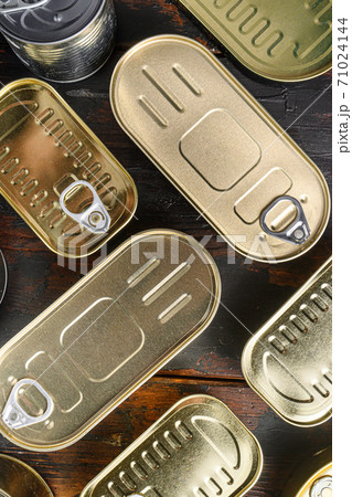 Various closed canned food, fish , fruits, vegetables, meat, soup different types of shapes top view on dark vintage table top view close up vertical 71024144