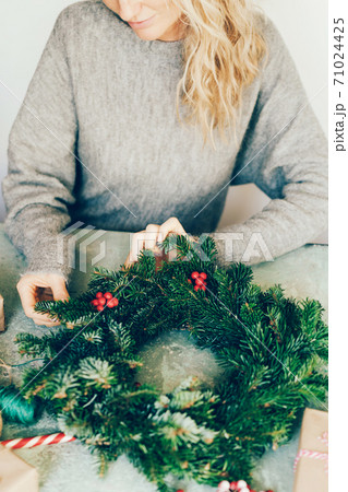 woman making christmas fir wreath 71024425