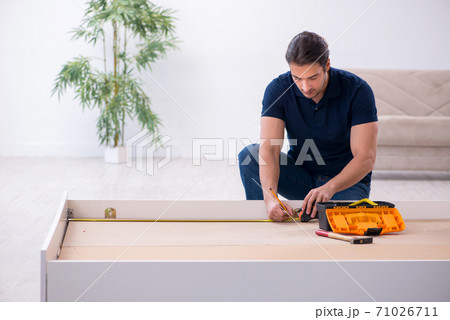 Young male contractor installing furniture at home Young male contractor installing furniture at home 71026711