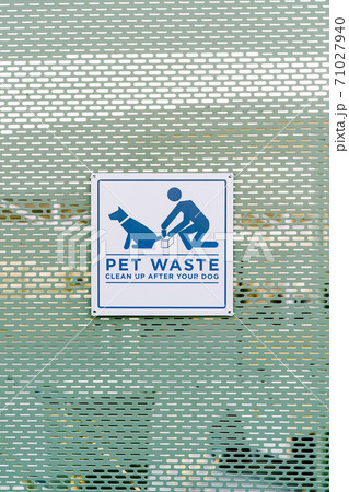 A sign on the fence with the inscription - PET WASTE, Clean up after your dog 71027940