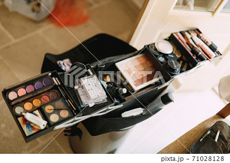 Makeup artist set. Large open cosmetic bag with eyeshadow, blush and lipstick in a bright room. 71028128