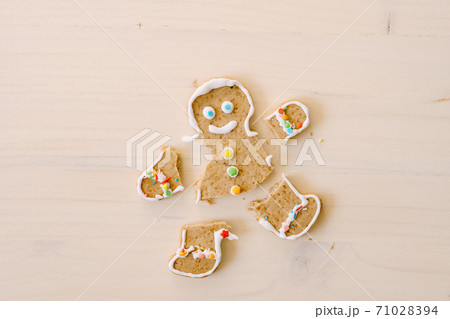 Gingerbread man with severed legs and arms. The limbs of the cookie are separated from the body. Christmas gingerbread on a white wooden background. 71028394