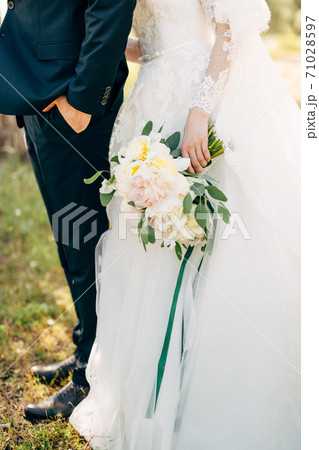 bride and groom standing together, bride is holding a bouquet 71028597