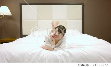 ホテルのベッドの上ではしゃいでいる女性	 ホテルのベッドの上ではしゃいでいる女性	 71029072