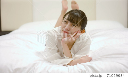 ホテルのベッドの上ではしゃいでいる女性	 71029084