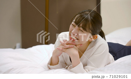 ホテルのベッドの上ではしゃいでいる女性	 71029101