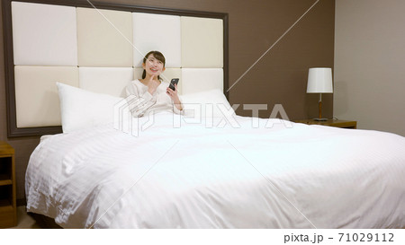 ホテルのベッドの上ではしゃいでいる女性 ホテルのベッドの上ではしゃいでいる女性 71029112