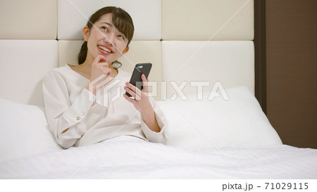 ホテルのベッドの上ではしゃいでいる女性 ホテルのベッドの上ではしゃいでいる女性 71029115