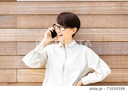 ウッドフェンス前で電話をする女性 71030398