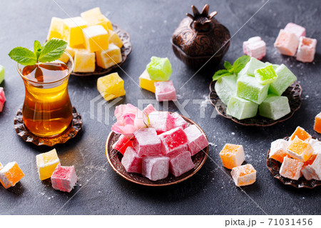 Assortment of Turkish delights on a copper tray with glass of tea. Grey background. Assortment of Turkish delights on a copper tray with glass of tea. Grey background. 71031456
