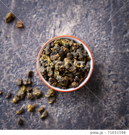 Green tea oolong in a clay tea cup bowl. Grey stone background. Close up. Top view. Green tea oolong in a clay tea cup bowl. Grey stone background. Close up. Top view. 71031598