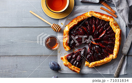 Plum galette with cup of tea. Grey wooden background. Copy space. Top view. Plum galette with cup of tea. Grey wooden background. Copy space. Top view. 71031634