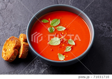 Tomato soup with basil in a bowl. Grey background. Close up. Top view. 71031710