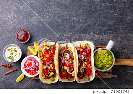 Taco with meat and vegetables on cutting board. Grey background. Copy space. Top view. Taco with meat and vegetables on cutting board. Grey background. Copy space. Top view. 71031742