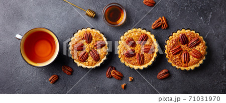 Pecan pies, mini tarts with cup of tea. Dark background. Close up. Top view. Pecan pies, mini tarts with cup of tea. Dark background. Close up. Top view. 71031970