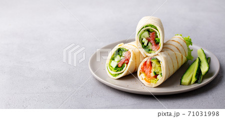 Wrap sandwich, roll with fish salmon and vegetables. Grey background. Close up. Copy space. 71031998