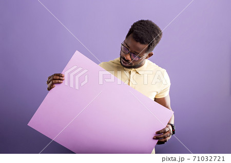 Picture of young african american man holding blank board on violet background Picture of young african american man holding blank board on violet background 71032721