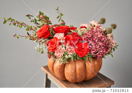 Flowers arrangement in pumpkin on wooden table. Fresh cut flowers for decoration home. European floral shop. Delivery fresh cut flower. 71032813