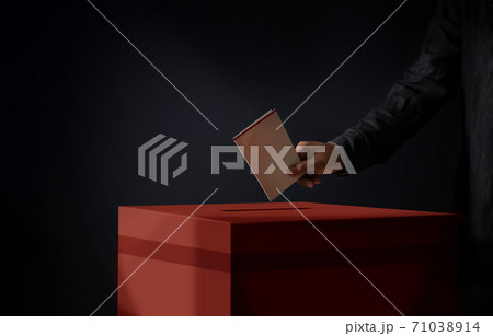 Election Concept. Person Dropping a Ballot Card into the Vote Box, Dark Cinematic Tone Election Concept. Person Dropping a Ballot Card into the Vote Box, Dark Cinematic Tone 71038914
