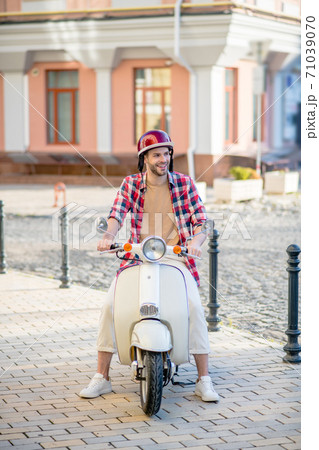 Man riding a scooter through the sidewalk 71039070