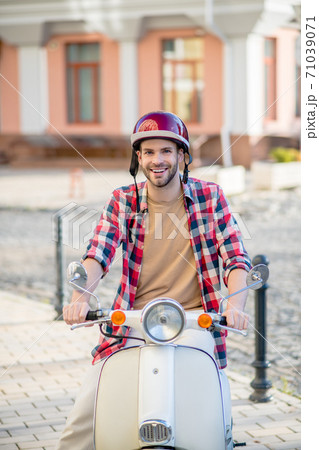 Man wearing a helmet riding his white scooter 71039071