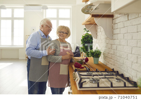 Happy senior couple cooking healthy veggie meal standing at countertop in the kitchen 71040751