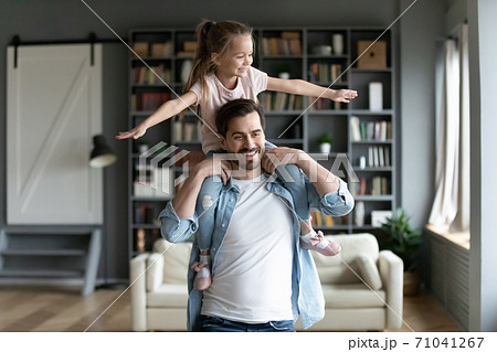 Happy young man holding on shoulders playful little preschool daughter. Happy young man holding on shoulders playful little preschool daughter. 71041267