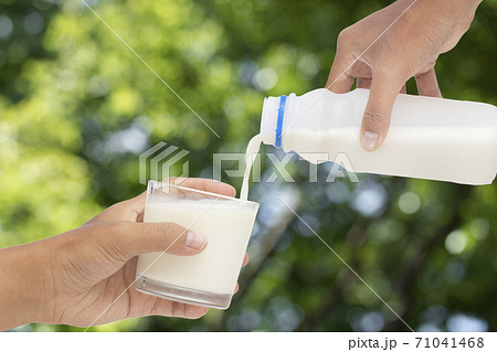 Pouring milk into glass on blurred leaves background. Pouring milk into glass on blurred leaves background. 71041468