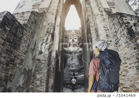 man with backpack looking old buddha in the temple at Sukhothai province. man with backpack looking old buddha in the temple at Sukhothai province. 71041469