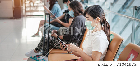Young female wearing face mask and using mobile smartphone in airport, protection Coronavirus disease (Covid-19) infection, Asian woman traveler sitting on chair. New Normal and social distancing 71041975