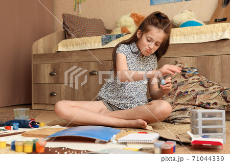 girl draws at home, artistic creation, makes creative artwork from paper, paints and brushes 71044339