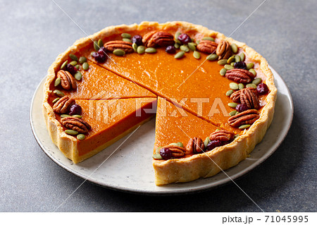Pumpkin pie with pecan nuts on a plate. Grey background. Close up. 71045995